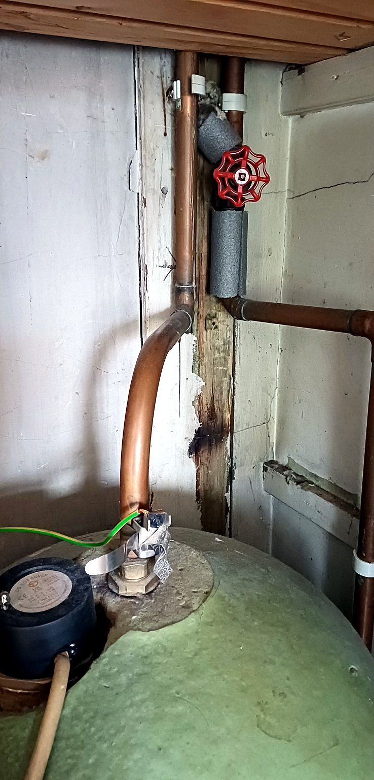 A copper hot water cylinder with a red gate valve on new copper pipework